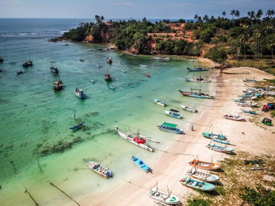 Vissersboten voor de kust bij een palmenstrand in Sri Lanka tijdens de 15-daagse fietsreis.