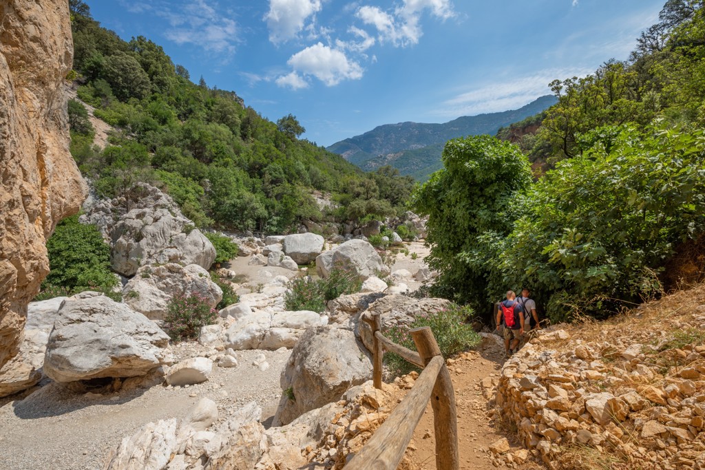 Wandelaars op een rotsachtig pad door een groene kloof in Sardinië, Italië.