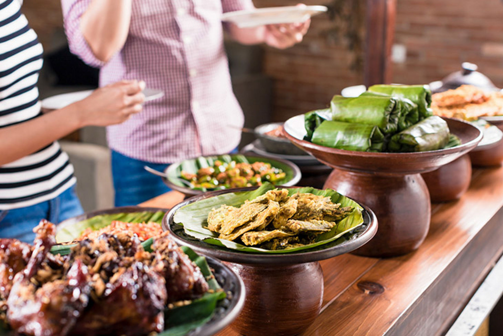 Eten in Indonesië Buffet met lokale gerechten geserveerd op bananenblad, met schalen op een houten tafel.
