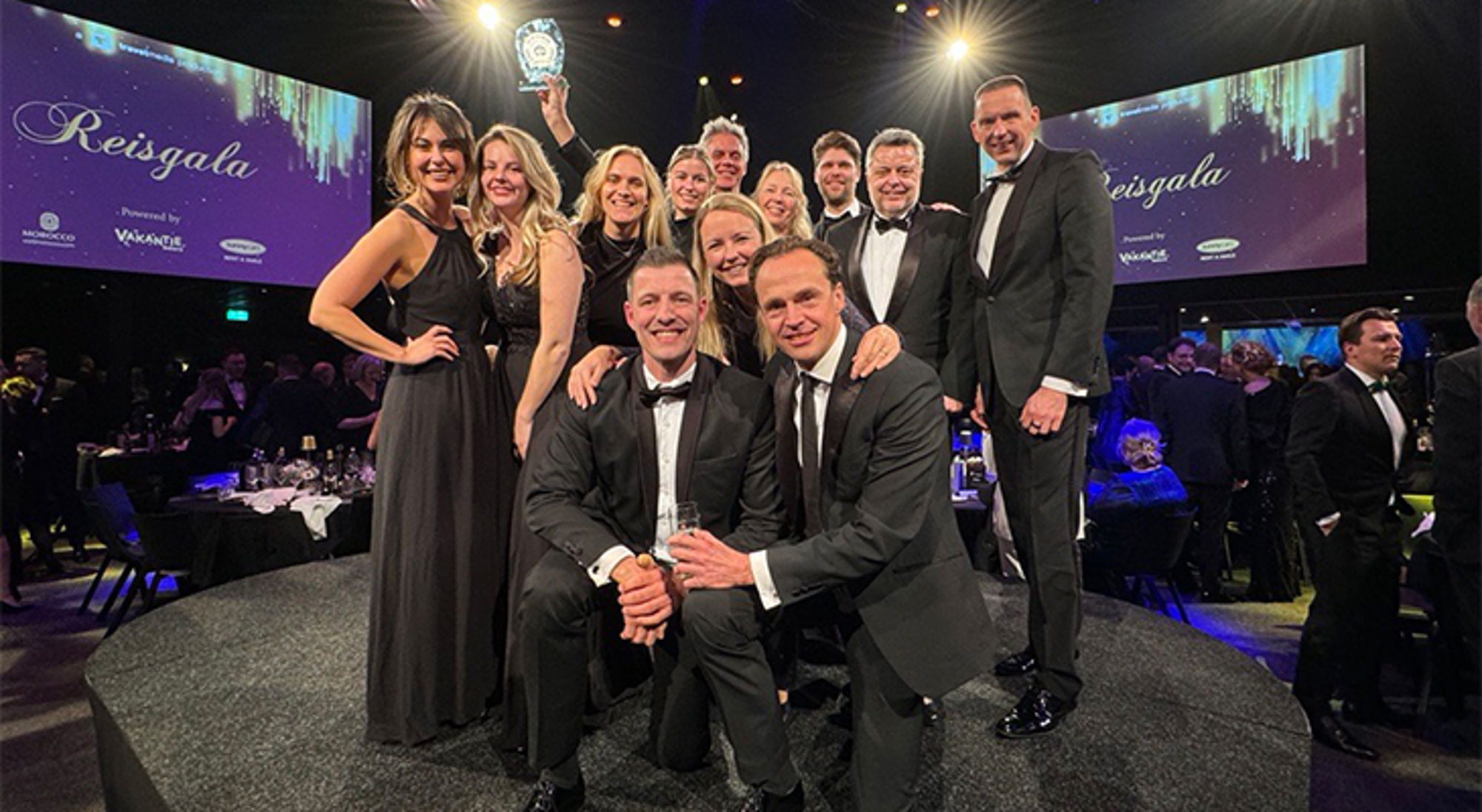 Reisgala 2024 Groepsfoto van winnaars op de Reisgala-awardshow in gala, met award op het podium.