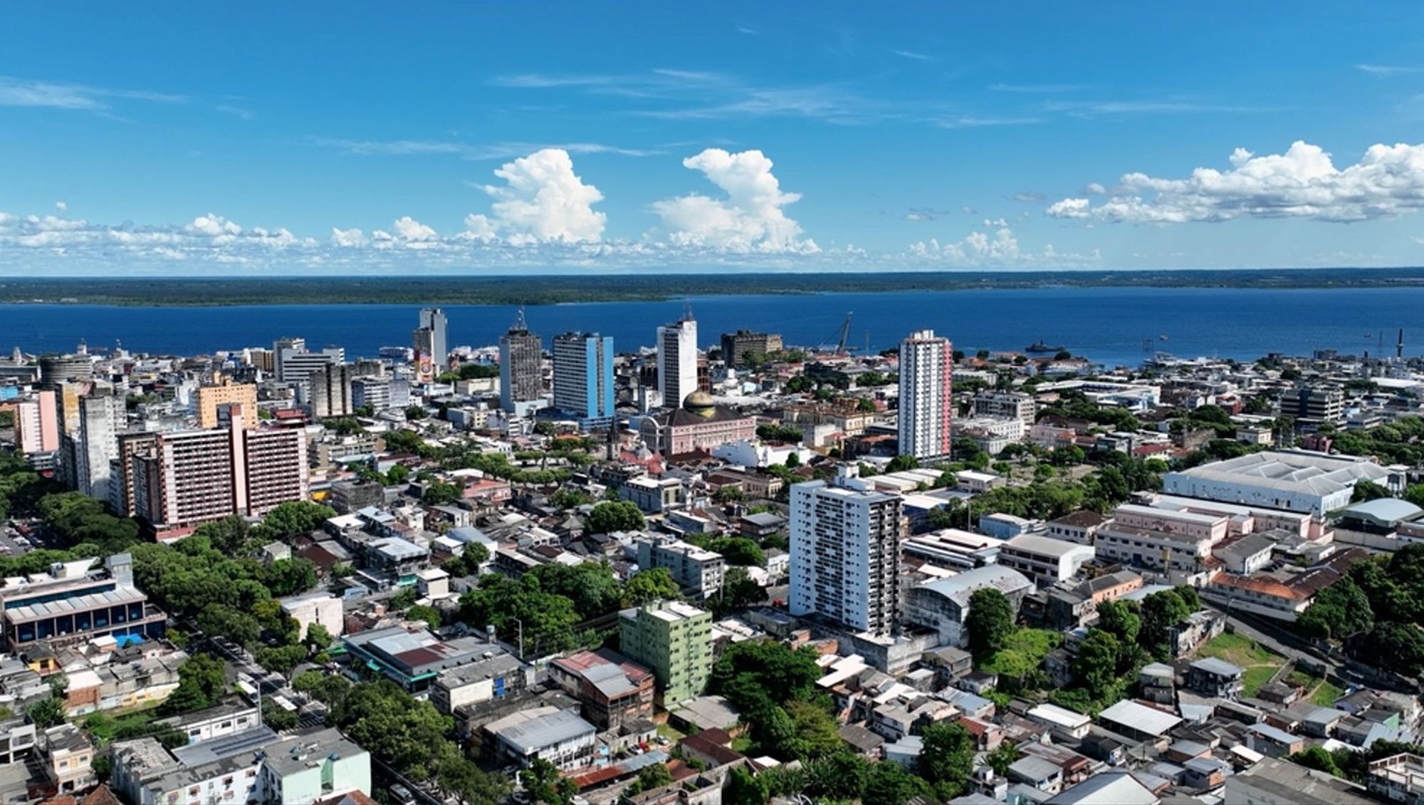 Skyline van Manaus aan de Rio Negro in Brazilië, met hoogbouw en haven onder een blauwe lucht.