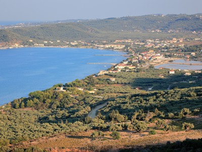 Uitzicht over de kust van Kefalonia met olijfgaarden en een dorp aan zee tijdens een Griekenland familiereis.