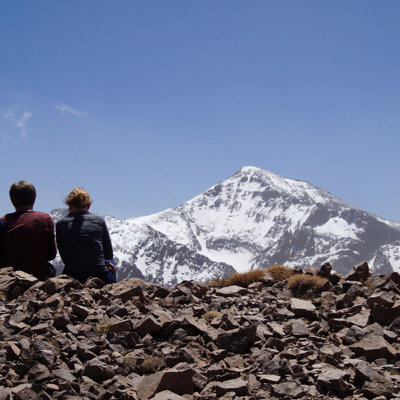 Wandelaars kijken uit op de besneeuwde top van Mount Toubkal tijdens een wandelvakantie in Marokko.