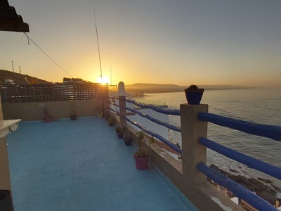 Zonsondergang vanaf een dakterras met uitzicht op zee aan de Marokkaanse kust.