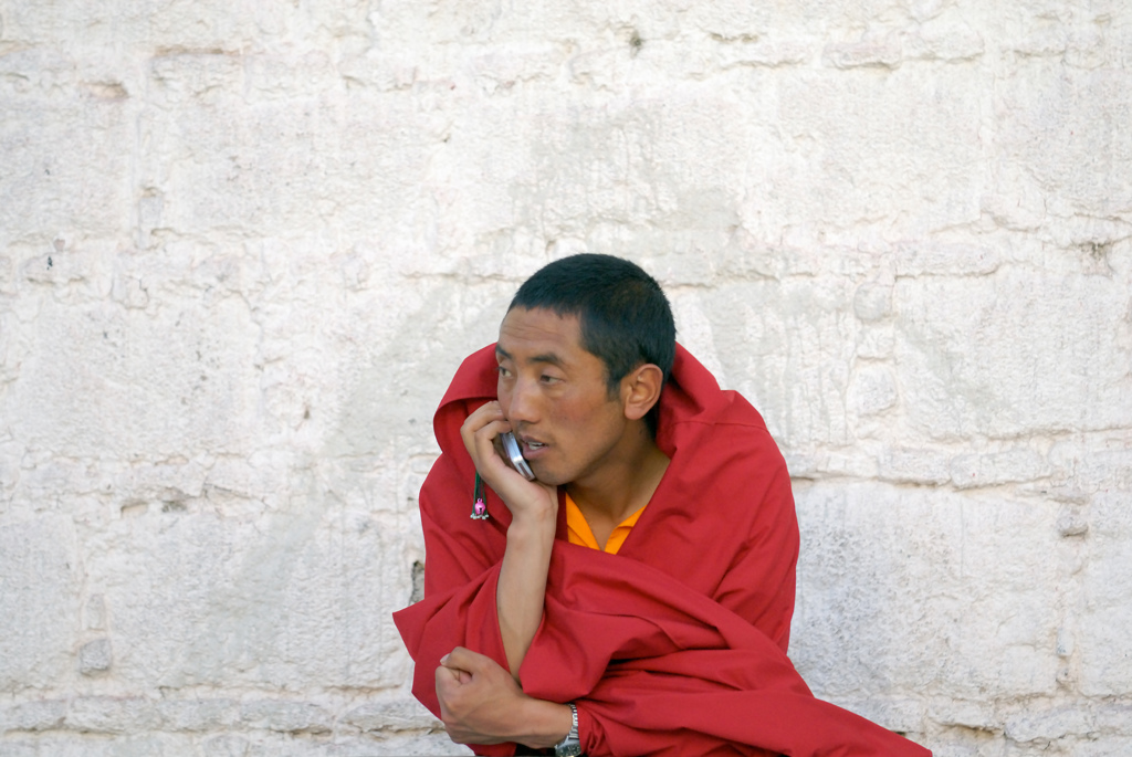 Monnik in rood gewaad belt met een mobiele telefoon tijdens groepsrondreis Tibet en Nepal.