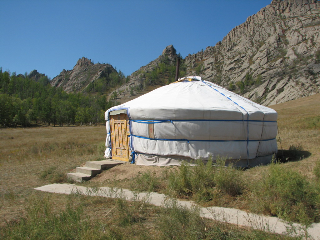 Witte Mongoolse yurt in een vallei met rotsachtige bergen tijdens de rondreis Trans-Siberië Expres.