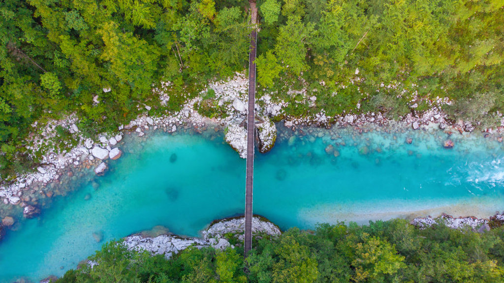een brug over een turquoise rivier in Slovenië tijdens een fietsvakantie.