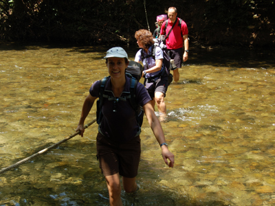 Wandelaars steken een ondiepe rivier over tijdens de Route Kalimantan.