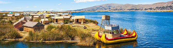 Rieteilanden op het Titicacameer bij Puno, Peru, met rieten huizen en traditionele boot aan de oever.