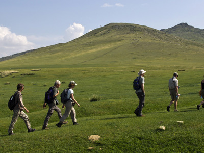 Wandelaars trekken door de groene heuvels van Mongolië tijdens de 23-daagse route.