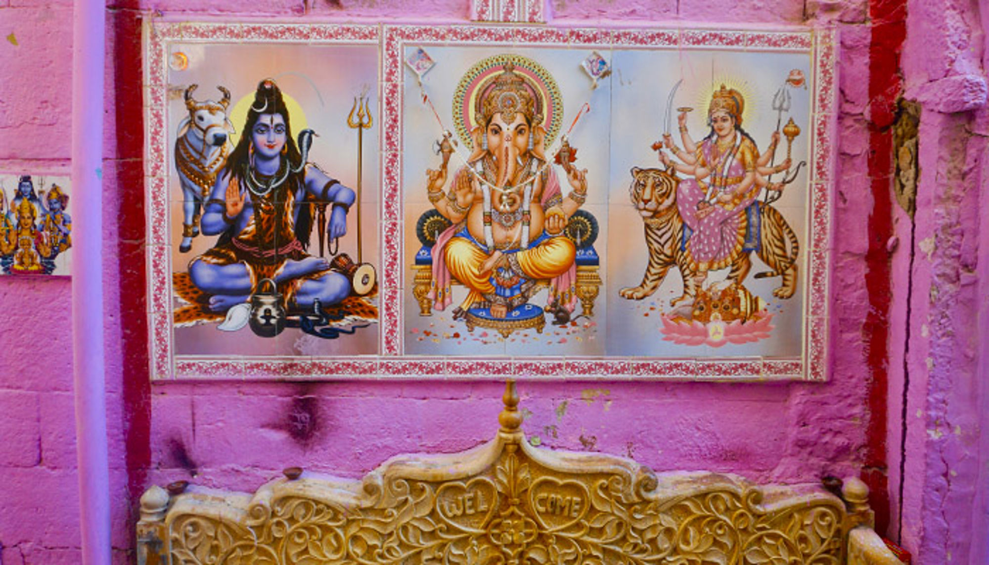Muurschildering in India Kleurrijke muurschildering met hindoegoden Shiva, Ganesha en Durga op tijger tegen een roze muur.