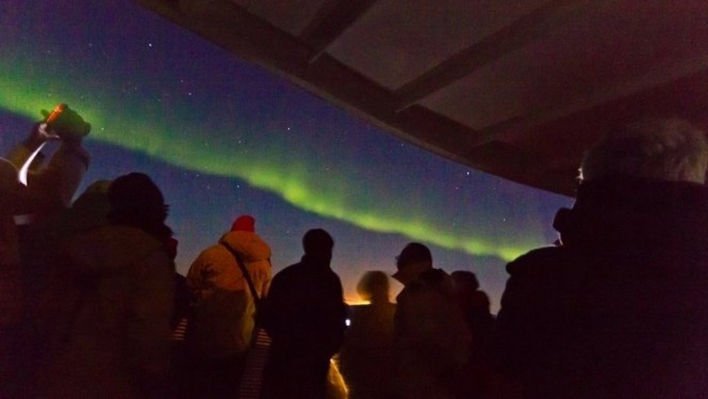 Groen noorderlicht boven het besneeuwde landschap van Groenland.