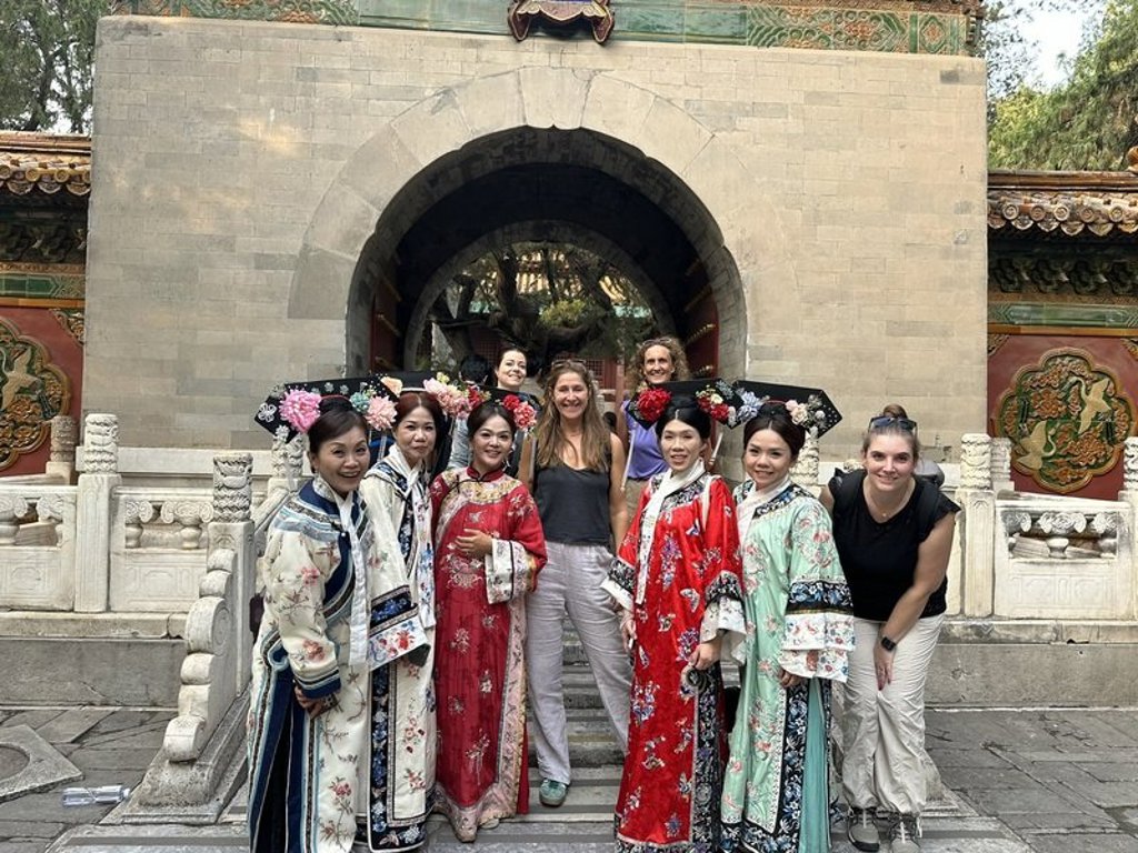 Groepsrondreis China hoogtepunten: reizigers poseren met vrouwen in traditionele kledij bij een tempelpoort.