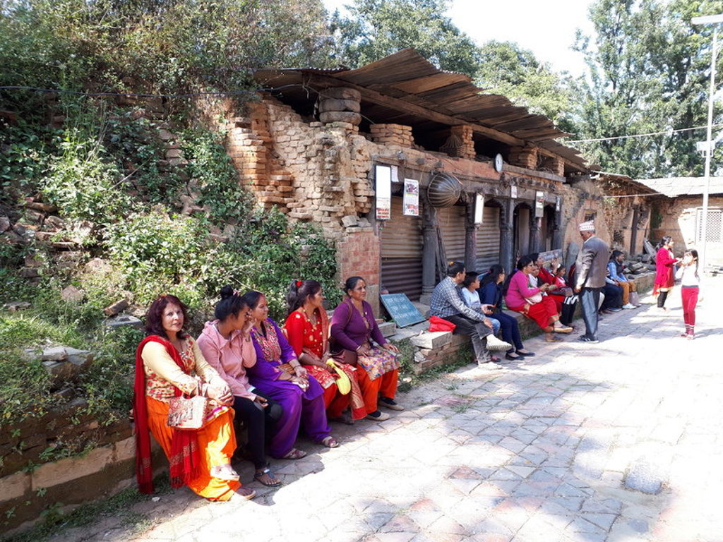 Lokale bewoners zitten langs een straat met oude gebouwen tijdens een familiereis Nepal.
