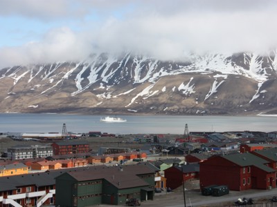 Longyearbyen op Spitsbergen met kleurrijke huizen aan de fjord en besneeuwde bergen op de achtergrond.