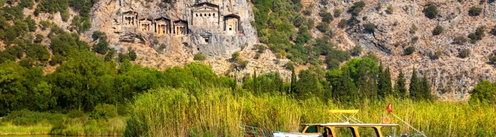 Rotsgraven van Kaunos boven de Dalyan-rivier, met een boot op het water in Turkije.