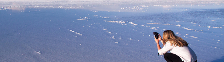 Reiziger fotografeert de uitgestrekte zoutvlakte Salar de Uyuni in Bolivia onder een blauwe lucht.