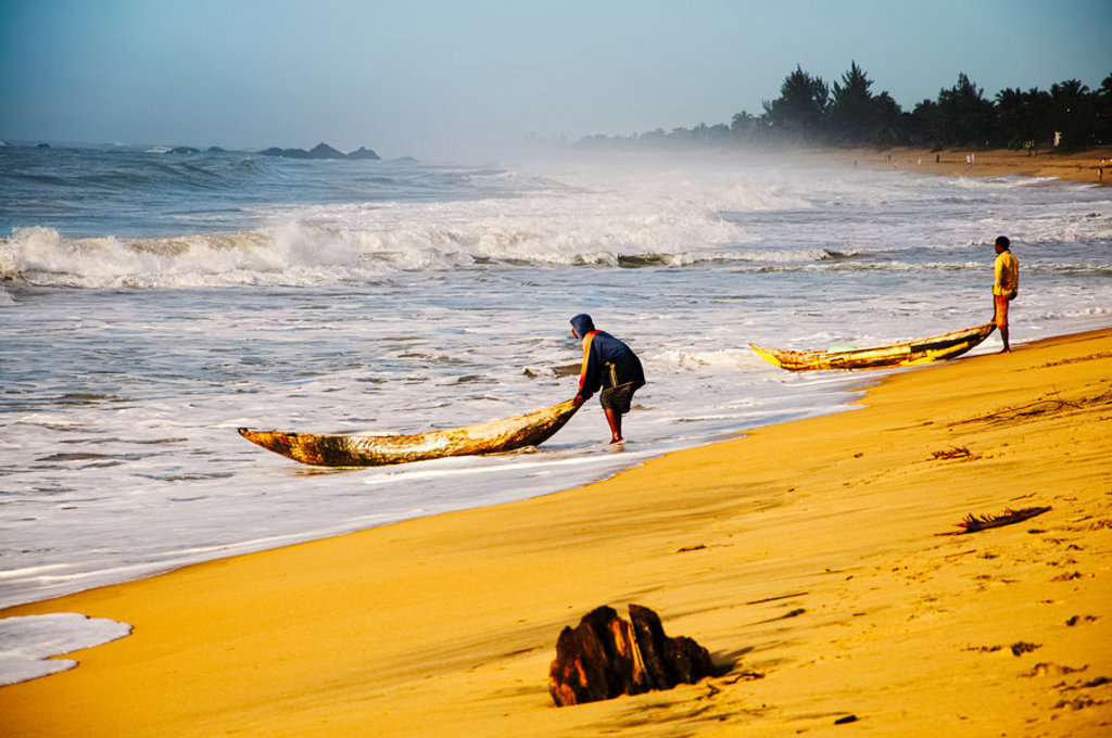 Vissers met houten kano’s op het strand van Madagascar bij de branding.