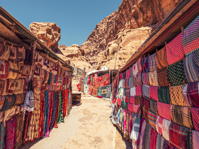 Marktkraampjes met kleurrijke sjaals en doeken in Petra, langs de route door Jordanië.