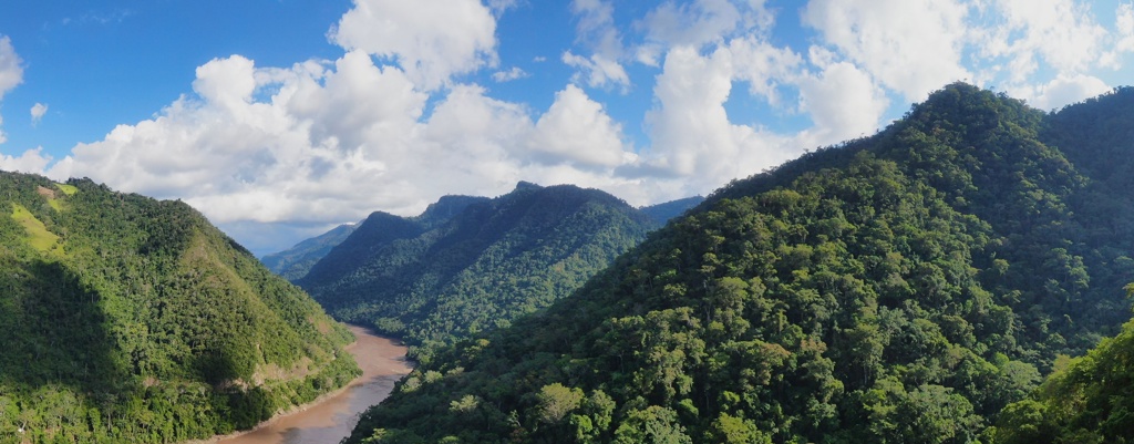 Groene Amazonejungle en rivier tussen bergen in Peru tijdens een 22-35ers groepsreis.