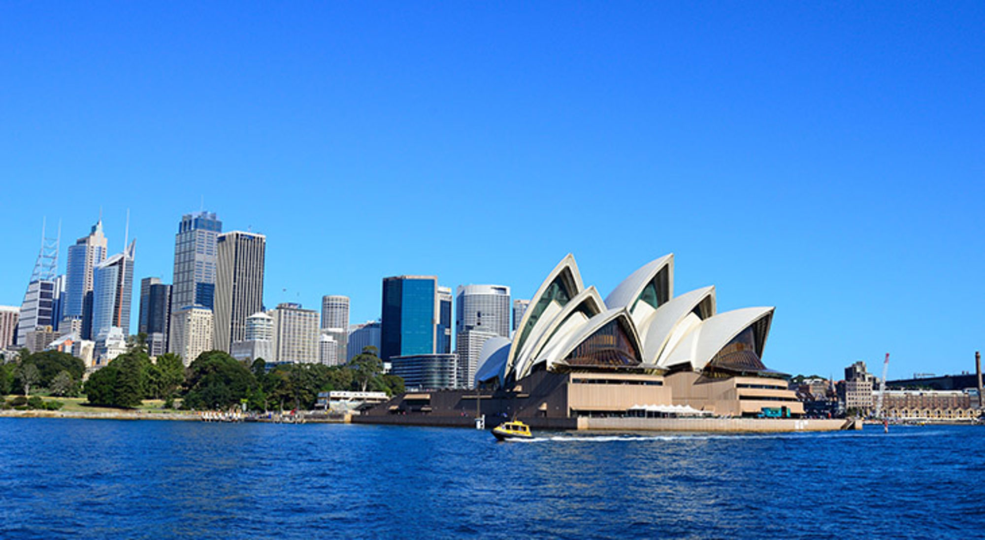 De mooiste stad ter wereld Sydney Sydney Opera House en skyline aan de haven, met een boot op het water.