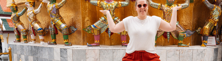 Fleur poseert bij kleurrijke tempelwachters in Thailand tijdens de 22-35ers reis.