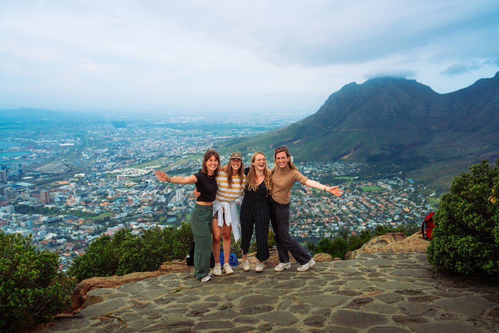 22-35ers reizen Zuid-Afrika: vriendinnengroep op uitzichtpunt met Kaapstad en Tafelberg op de achtergrond.