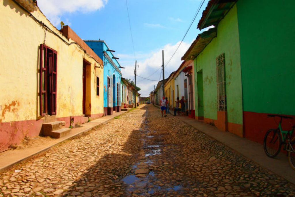 Kleurrijke straat met kinderkopjes en pastelkleurige huizen in Cuba tijdens de familiereis Cuba Hoogtepunten.