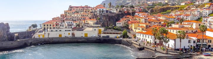 Kustplaats in Portugal met kleurrijke huizen en rode daken rond een beschutte baai.