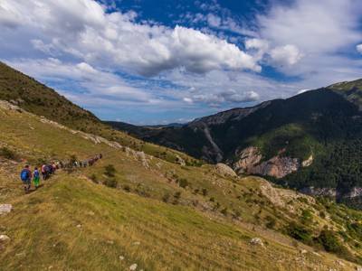 Wandelaars op bergpad met uitzicht op groene valleien en rotswanden in Bosnië & Herzegovina.