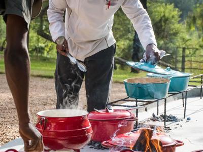 Kok bereidt een maaltijd in gietijzeren potten boven open vuur tijdens de route door Zuid-Afrika.