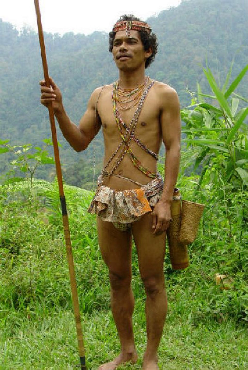Man in traditionele klederdracht met speer in het regenwoud van Maleisië tijdens rondreis Maleisië hoogtepunten.