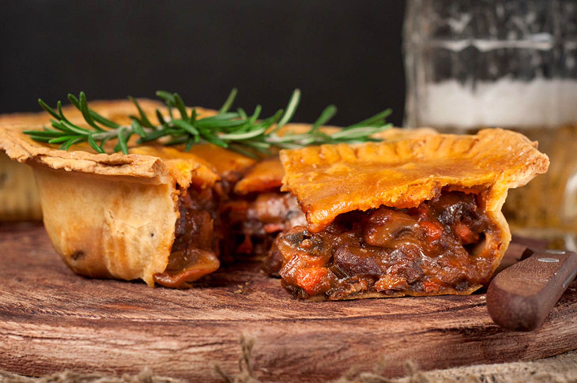 Eten in Australië Hartige vleespastei met rozemarijn, doorgesneden op een houten plank.