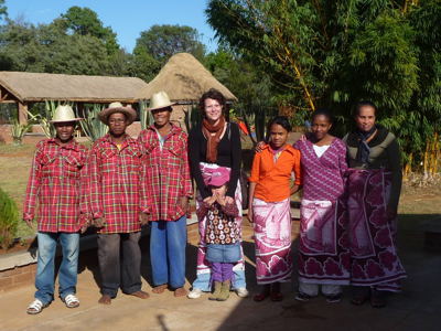 Groepsfoto met lokale bewoners en reizigers tijdens de 25-daagse Madagascar-rondreis, bij traditionele huizen.