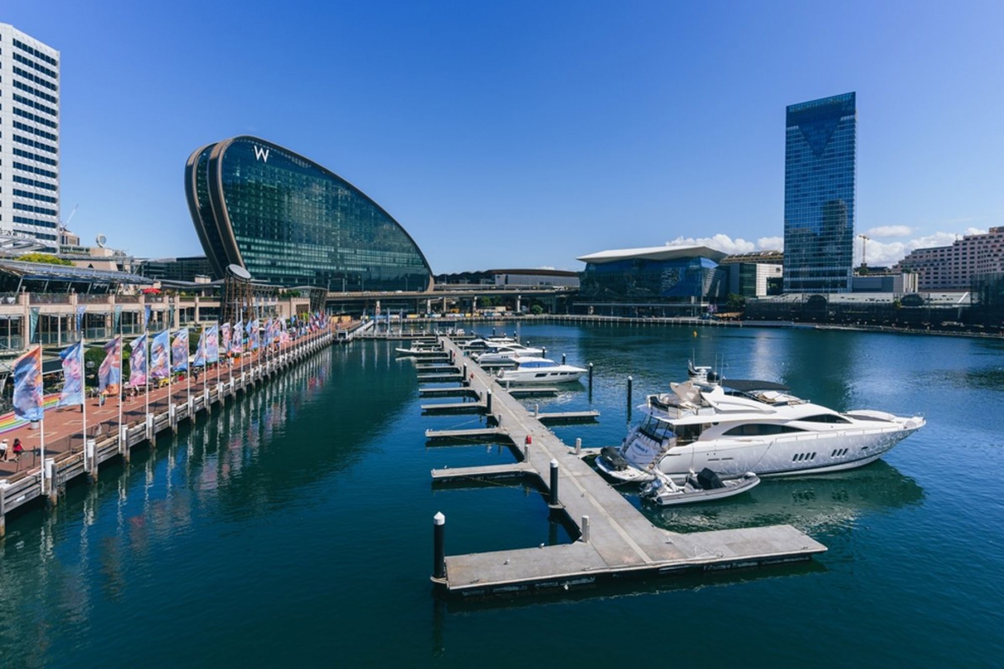 Darling Harbour in Sydney met jachthaven, luxe jacht en moderne skyline onder een blauwe lucht.