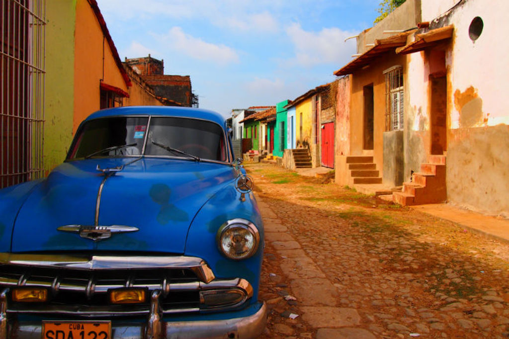 Blauwe klassieke auto in een kleurrijke straat in Cuba tijdens de familiereis Cuba Hoogtepunten.