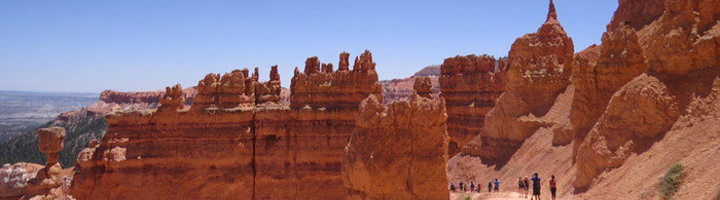 Wandelaars op pad tussen rode rotsformaties in het Wilde Westen, met uitzicht over de canyon.
