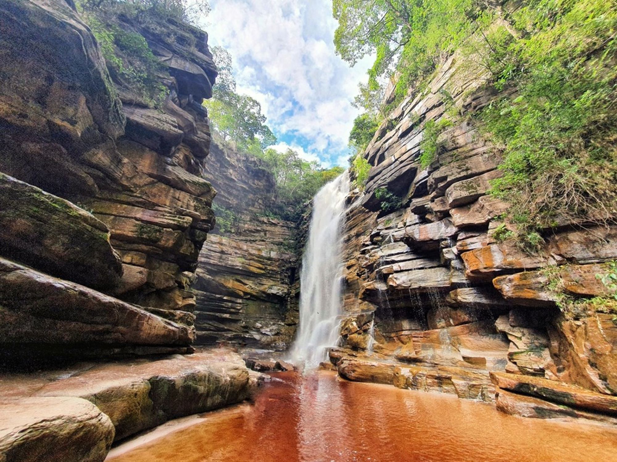 Waterval in een smalle rotskloof met roodkleurig water, Brazilië.