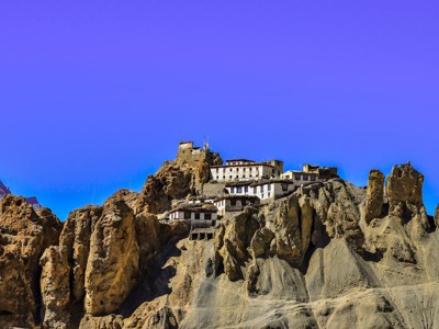 Kloostercomplex op een rots in Ladakh langs de route Spiti & Ladakh, met ruige bergpieken en heldere lucht.