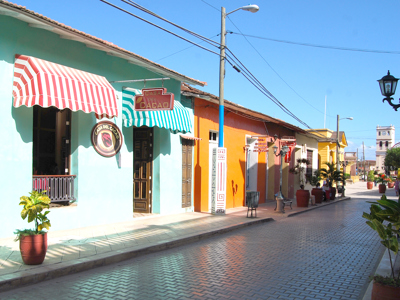 Kleurrijke straat in Baracoa, Cuba, met gevels en het bord Casa del Cacao.
