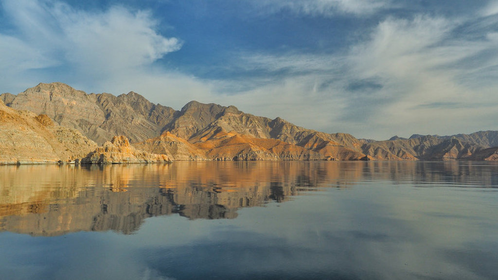 Berglandschap in Oman weerspiegeld in rustig water, tijdens groepsrondreis Oman en Dubai.