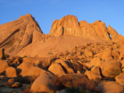 Rotsformaties bij Spitzkoppe in Namibië, verlicht door de ondergaande zon.