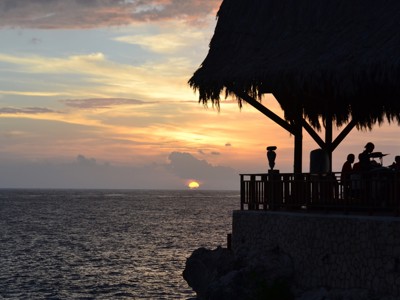 Zonsondergang boven zee bij een strandbar met rieten dak op Jamaica.