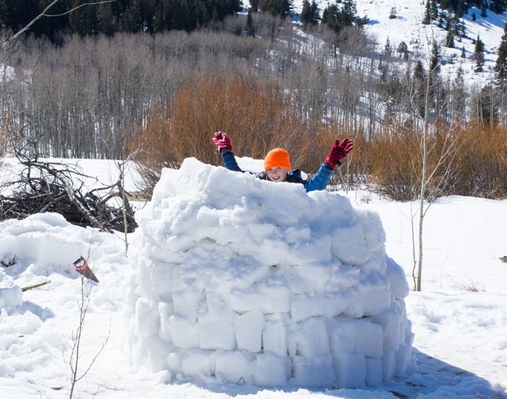Kind speelt in een sneeuwiglo tijdens familiereis Lapland Winter in Finland.