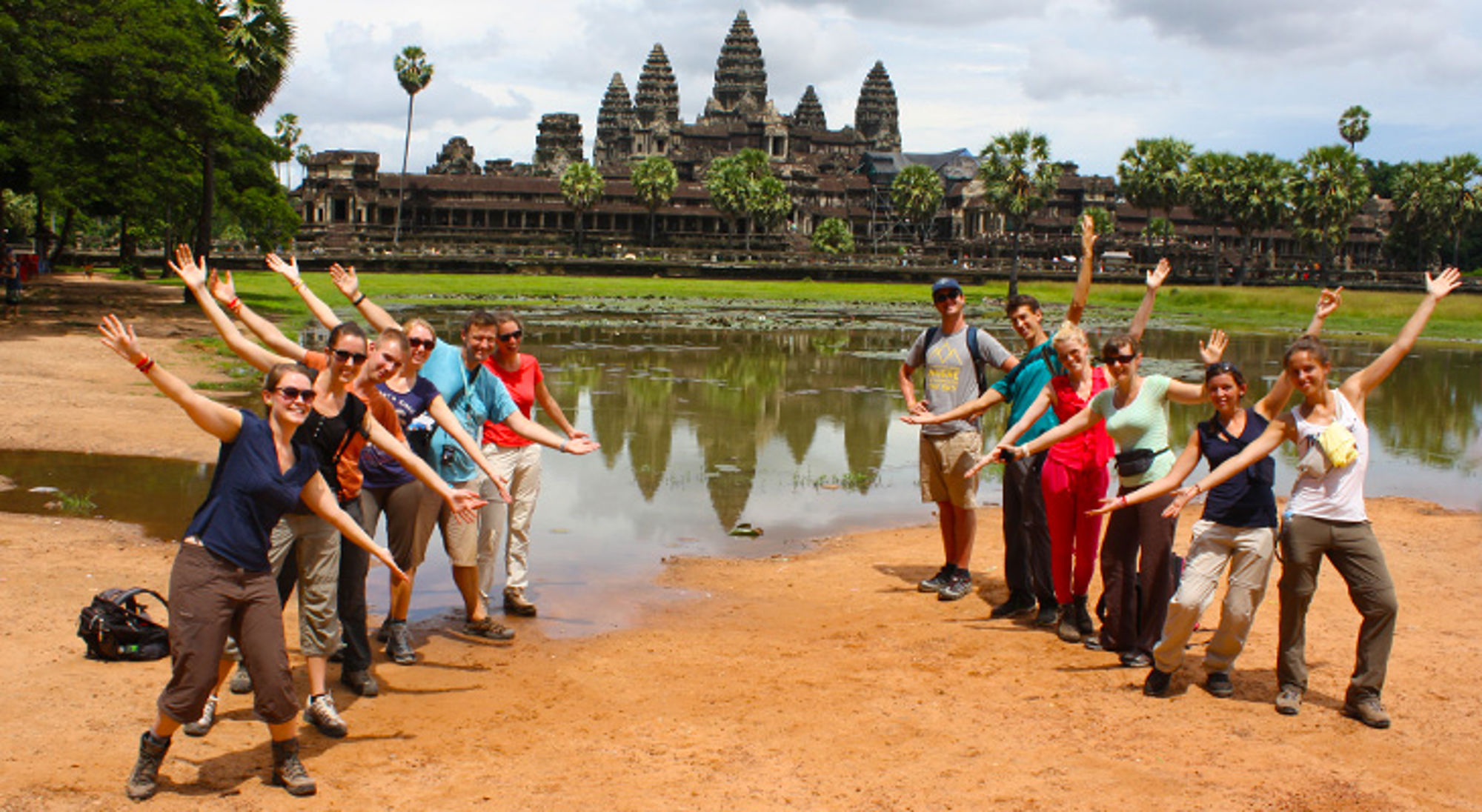 groepsfoto bij ankor wat in cambodja Groep reizigers poseert met opgeheven armen voor Angkor Wat in Cambodja.