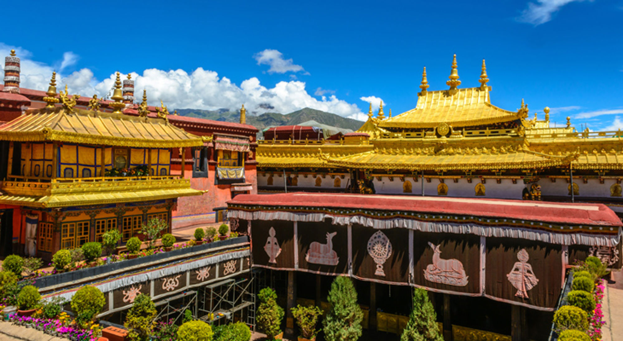 Lhasa in Tibet, een van de hoogste gelegen steden van de wereld Gouden daken en kleurrijke gebouwen van een Tibetaans kloostercomplex tegen bergen en blauwe lucht.