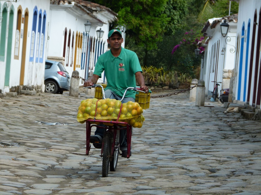 Man op bakfiets met citrusvruchten in een historisch straatje tijdens familiereis Argentinië en Brazilië.