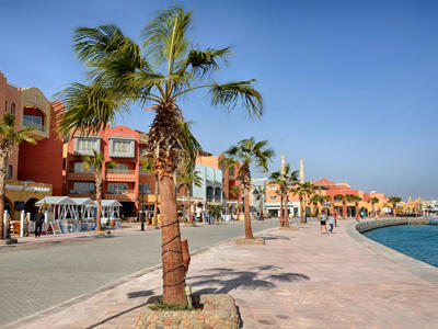 Boulevard met palmbomen en kleurrijke gebouwen aan de jachthaven in Hurghada, Egypte.