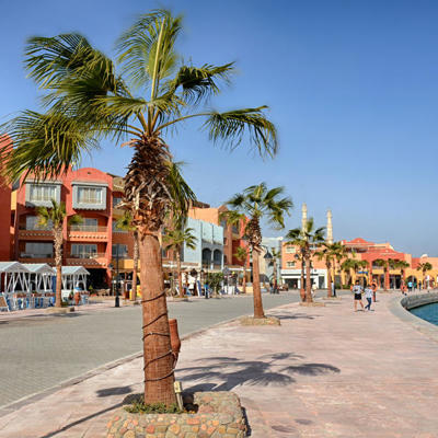 Boulevard met palmbomen en kleurrijke gebouwen aan de jachthaven in Hurghada, Egypte.