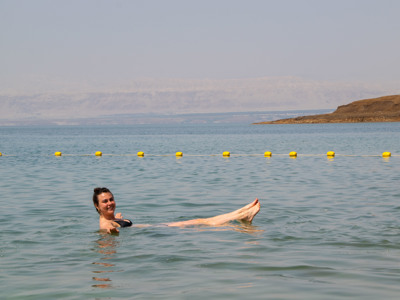 Vrouw drijft in de Dode Zee in Jordanië, met bergen op de achtergrond.